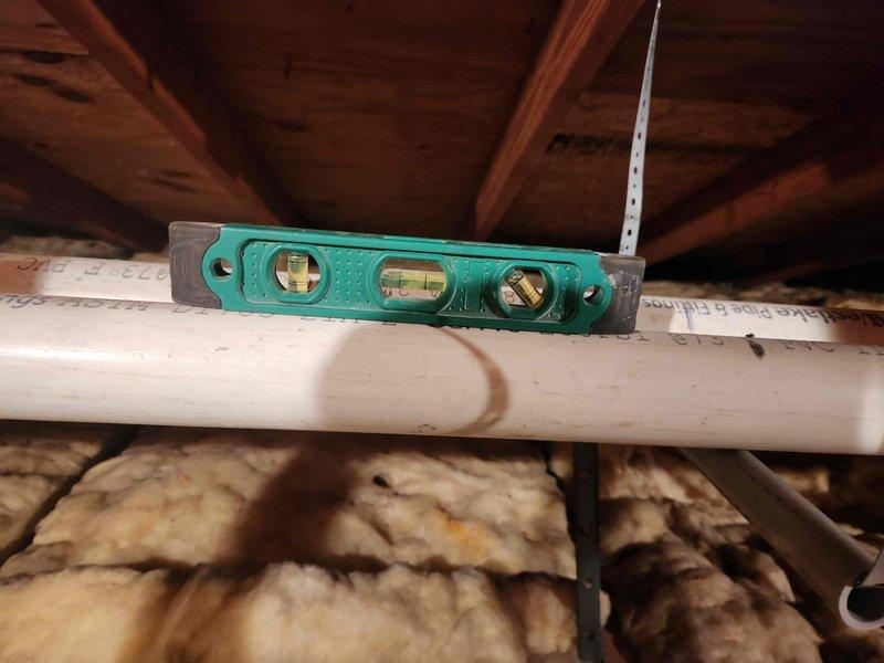 Completed boiler installation with Honeywell zone control system mounted on wooden panel, properly labeled for different rooms including Living Room and Family Room. Ensured proper leveling of PVC piping in the attic space and verified insulation integrity around installation area. Temporary space heaters were returned as requested.