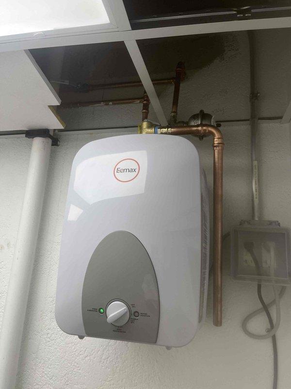 Diagnosed leaking EEmax tankless water heater, finding moisture accumulation on internal components. Inspection revealed condensation around electrical connection point with visible water droplets on terminal connections, creating potential hazard. Unit requires replacement due to internal water intrusion compromising electrical system integrity.
