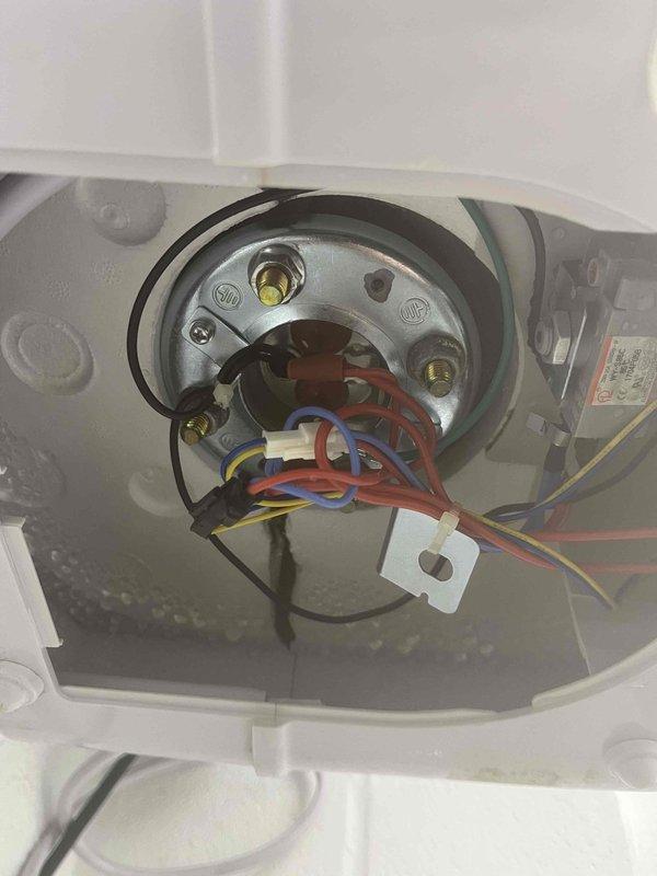 Diagnosed leaking EEmax tankless water heater, finding moisture accumulation on internal components. Inspection revealed condensation around electrical connection point with visible water droplets on terminal connections, creating potential hazard. Unit requires replacement due to internal water intrusion compromising electrical system integrity.