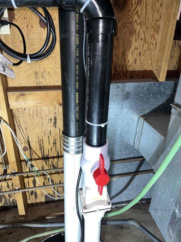 Returned to complete installation of previously sold grinder pump system with check valve and crock lid. Installed ABS and PVC piping with shut-off valve in basement utility area. Installation included securing base plate to floor and connecting discharge piping. Materials on order; work scheduled for completion upon delivery.