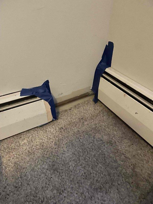 Inspected baseboard heating system for reported metal component issues. Observed water damage on adjacent wall with visible stains and cracks. Applied protective tape at corner junctions of baseboard units in preparation for necessary repairs to restore proper heating function.