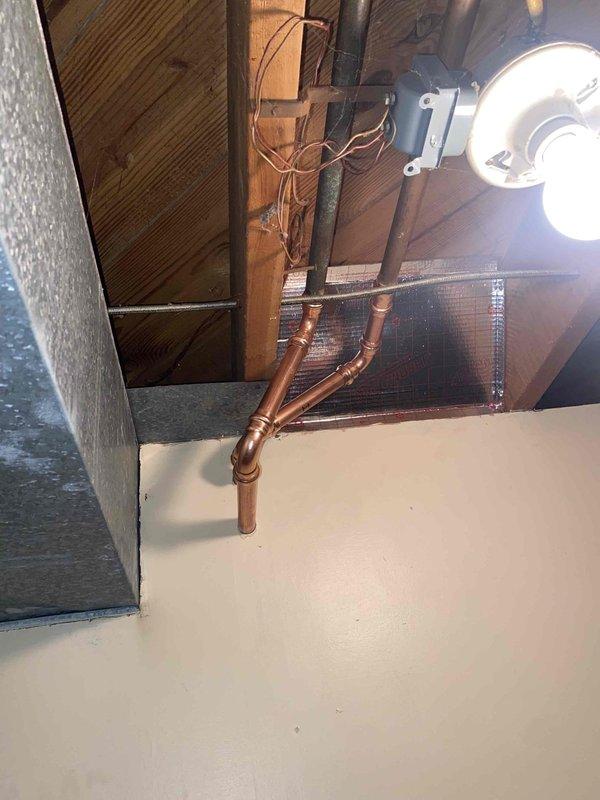 Completed installation of a tanked water heater with associated copper pipe connections and expansion tank (labeled 602022/602). Installation included proper mounting of the expansion tank, connection to existing plumbing system, and installation of control valves including red-handled and blue-handled shutoffs. All connections were verified secure with no leaks observed.