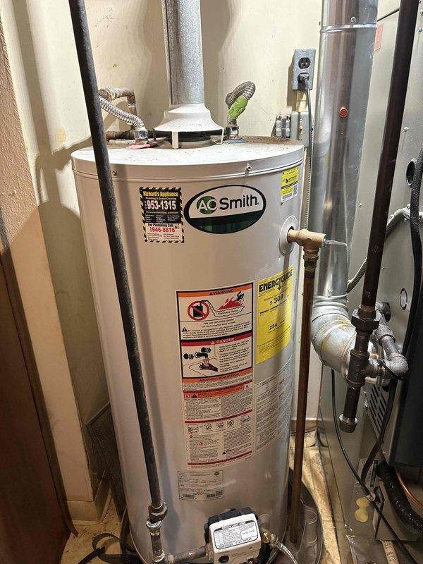Responded to emergency call for leaking water heater. Upon inspection, identified an aging A.O. Smith gas water heater with visible corrosion and rust spots on tank surface. Determined the unit had reached end of service life with tank integrity compromised. Recommended immediate replacement to prevent potential water damage.