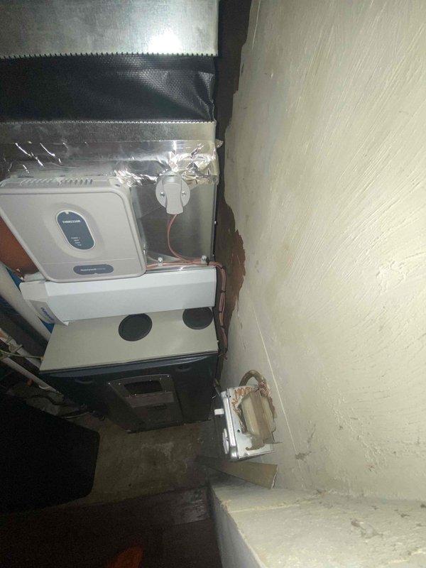 Assessed furnace installation in non-riser configuration requiring removal for ductwork access. Existing HVAC system includes water filtration components and a white rectangular air handler unit mounted against wall with black insulated ductwork above. Coordination with ductwork team required for proper sequencing of removal and reinstallation.