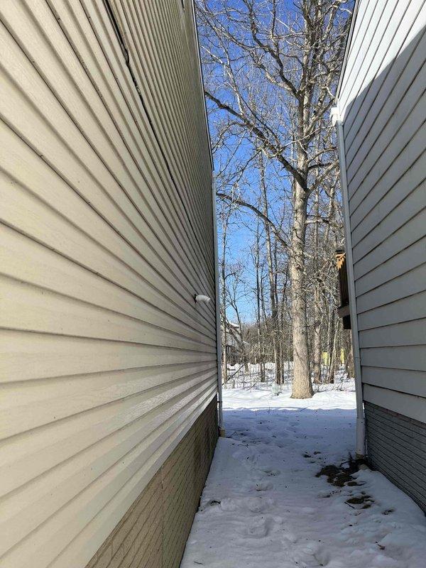 Responded to follow-up service call for reported loud blower motor in air handler. Accessed unit through narrow passageway between residential structures during winter conditions. Inspected water heating system and adjacent HVAC equipment in utility area, identifying and resolving noise issue with the blower assembly.