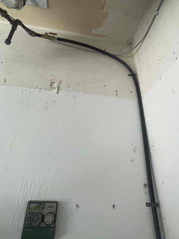 Completed gas piping installation with brass valve and flexible gas line connection in wall cavity. Installation included securing line with appropriate bracketing and connecting to existing metal piping system. Coordinated work with roofing contractor as per service agreement.