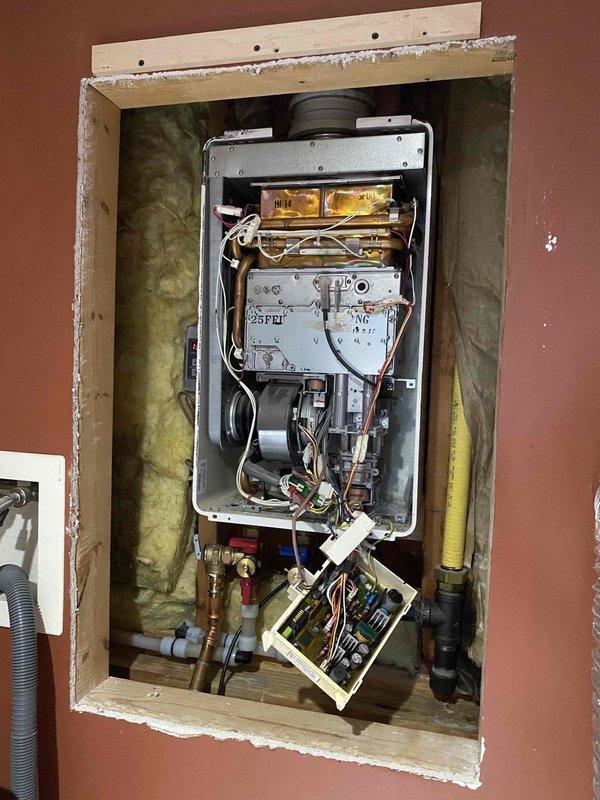Diagnosed non-operational Rinnai R53 tankless water heater (15-20 years old) with significant internal component deterioration. Inspection revealed circuit board failure and compromised wiring harnesses requiring complete unit replacement. Measurements were taken of existing installation space to ensure proper sizing for replacement unit.