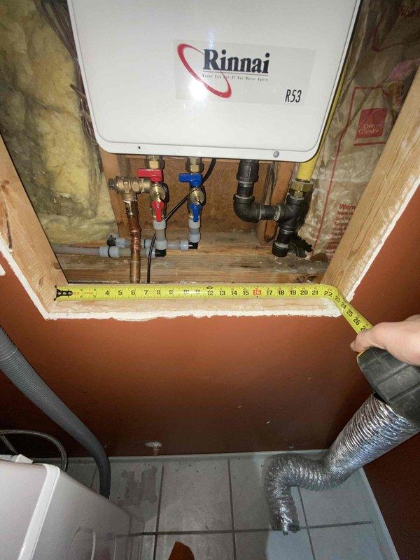 Diagnosed non-operational Rinnai R53 tankless water heater (15-20 years old) with significant internal component deterioration. Inspection revealed circuit board failure and compromised wiring harnesses requiring complete unit replacement. Measurements were taken of existing installation space to ensure proper sizing for replacement unit.