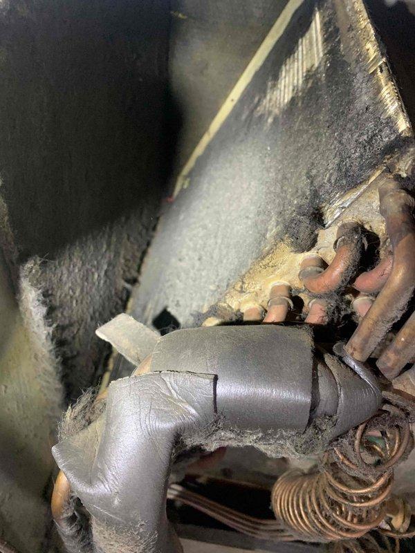 Responded to service call for suspected thermostat malfunction in mobile home. Visual inspection revealed significant frost buildup on evaporator coils and copper lines, indicating possible refrigerant flow issues. System appears to be an older unit with considerable dust accumulation and normal wear on components.