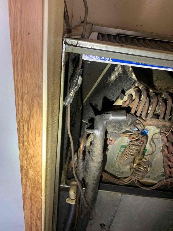 Responded to service call for suspected thermostat malfunction in mobile home. Visual inspection revealed significant frost buildup on evaporator coils and copper lines, indicating possible refrigerant flow issues. System appears to be an older unit with considerable dust accumulation and normal wear on components.
