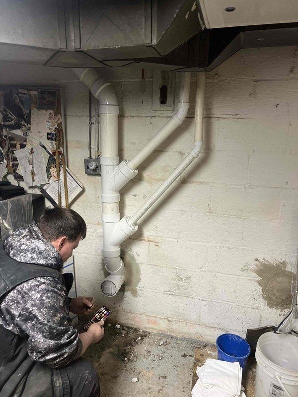 Completed relocation of sewer line by excavating trench in winter conditions and installing approximately 20 feet of new PVC piping to connect to existing sewer system. Successfully rerouted drainage configuration in basement utility area with proper elbow joints and vertical pipe arrangement, ensuring functional waste water discharge from the property.