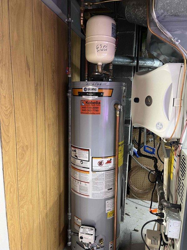 Completed installation of a 40-gallon standard vent water heater to replace existing unit. Noted the system connects to a shared WYE with previously installed furnace venting. Verified proper venting clearance and confirmed level installation of the new equipment with expansion tank properly mounted.