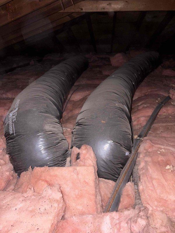 Inspected aging gas furnace system that was randomly shutting off. Examined attic ductwork configuration with dual black flexible ducts running through fiberglass insulation, and evaluated existing Lochinvar water heater installation. Recommended replacement of unreliable heating system with properly sized unit to resolve intermittent operation issues.