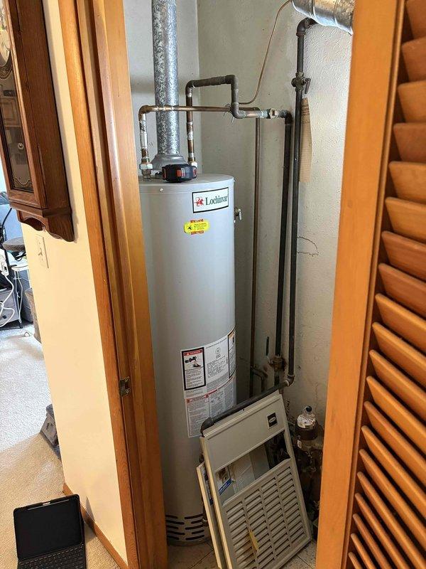 Inspected aging gas furnace system that was randomly shutting off. Examined attic ductwork configuration with dual black flexible ducts running through fiberglass insulation, and evaluated existing Lochinvar water heater installation. Recommended replacement of unreliable heating system with properly sized unit to resolve intermittent operation issues.