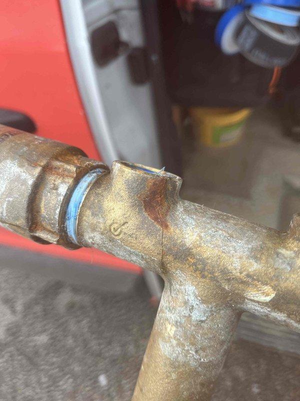 Cleared severe kitchen sink clog by accessing drainage system in basement where previous service attempt had failed. Inspected aged copper piping with visible corrosion at T-junction, then successfully used high-pressure equipment to remove blockage and restore proper drainage function.