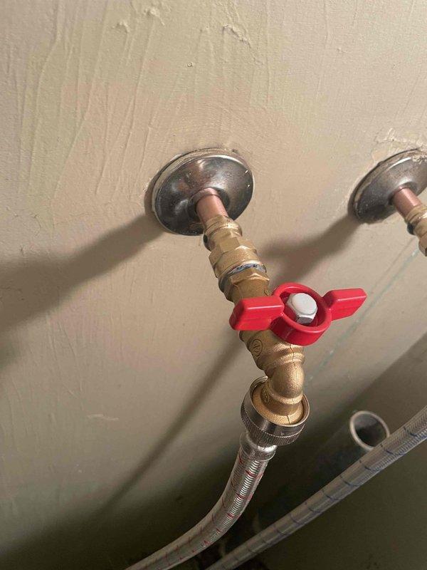 Replaced two deteriorating washer shut-off valves with new brass quarter-turn valves featuring red handles. Installed stainless steel braided supply lines for improved durability and leak prevention, ensuring proper water supply connection to the washing machine.