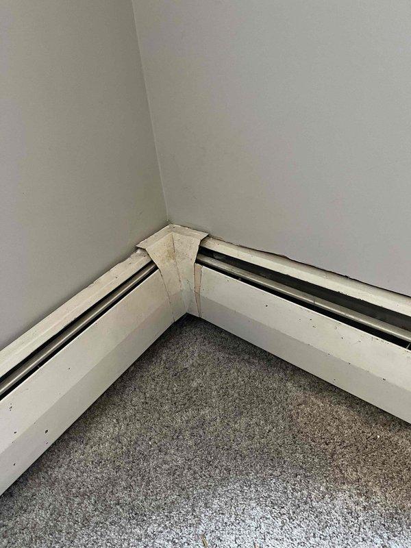 Conducted inspection of baseboard heating system to assess customer's concerns about radiators. Observed visible wear and damage at corner junction of baseboard heater cover with signs of separation. Evaluated confined installation space between wall and furniture that may be affecting proper heat distribution. Recommended options for repair versus replacement based on current system condition.