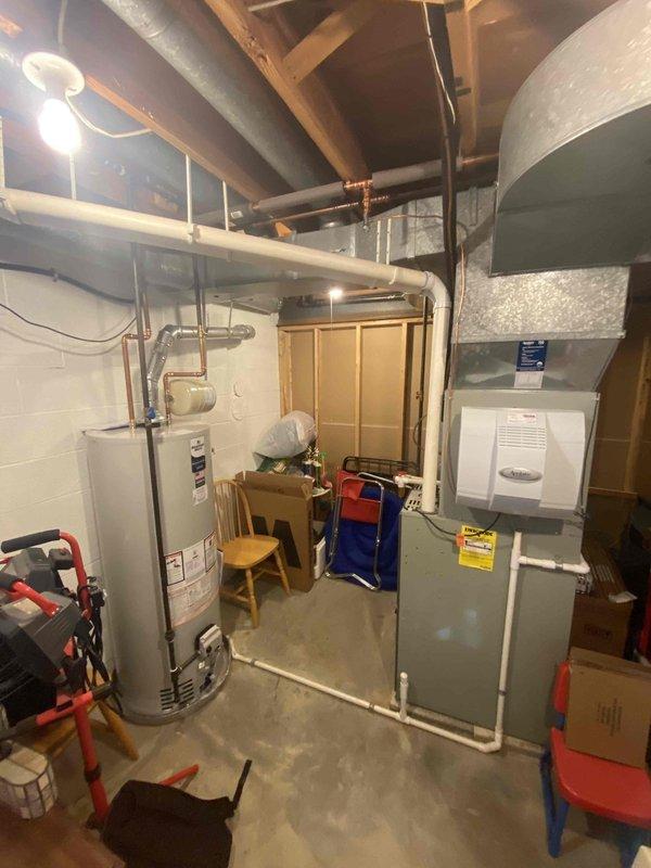 Conducted comprehensive assessment of 20-year-old furnace and same-age AC system, both currently operational. Inspected existing ductwork configuration and connections in utility space, noting metal ductwork condition and copper line placement. Evaluated basement mechanical room housing current furnace unit, water heater, and associated distribution systems for replacement feasibility.