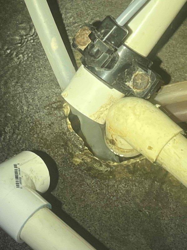 Responded to service call for water pooling under water softener tank. Upon inspection, identified leaking connection at PVC junction point with visible corrosion and mineral buildup. Replaced damaged black coupling and deteriorated PVC pipe sections, restoring proper function and eliminating leak.