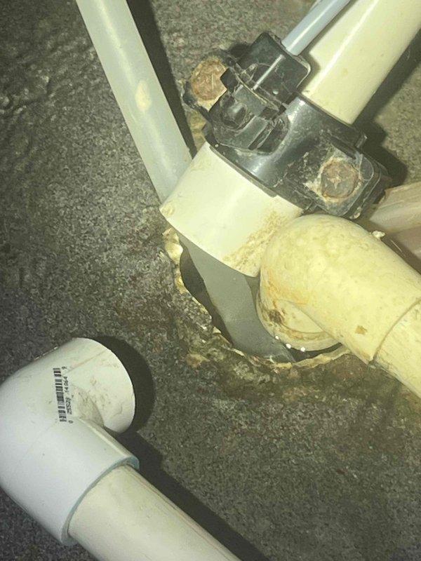 Responded to service call for water pooling under water softener tank. Upon inspection, identified leaking connection at PVC junction point with visible corrosion and mineral buildup. Replaced damaged black coupling and deteriorated PVC pipe sections, restoring proper function and eliminating leak.