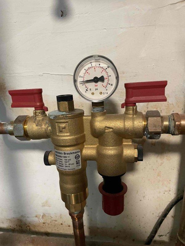 Responded to service call for a whistling boiler with low pressure gauge reading. Inspected the 25-year-old water heating system, including copper piping connections and pressure regulator valve assembly. Adjusted the Braukmann pressure reducing valve to correct the whistling issue and restore proper system pressure.