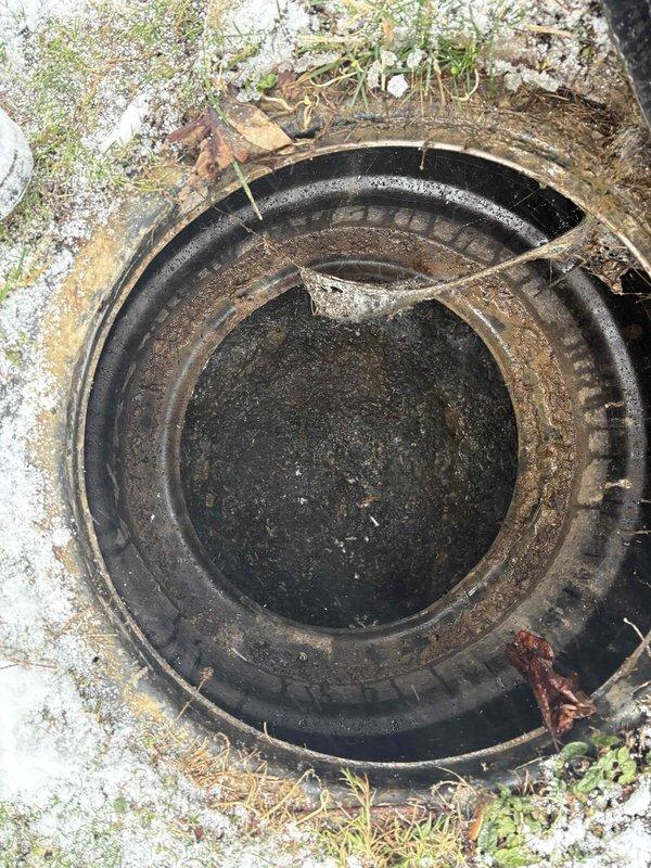 Cleared main line blockage causing backup through outdoor access point. Excavated snow-covered cleanout cap and removed accumulated sludge/sediment from drain system. After-hours service completed successfully; system now draining properly.