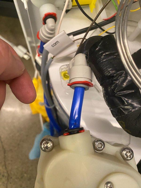 Responded to service call for commercial water treatment system showing error code with associated leak. Inspected quick-connect fittings on filtration unit where water line was leaking at connection point. Repaired compromised connection between blue/white tubing and plastic fittings, securing the system components and ensuring proper seal at the junction points.