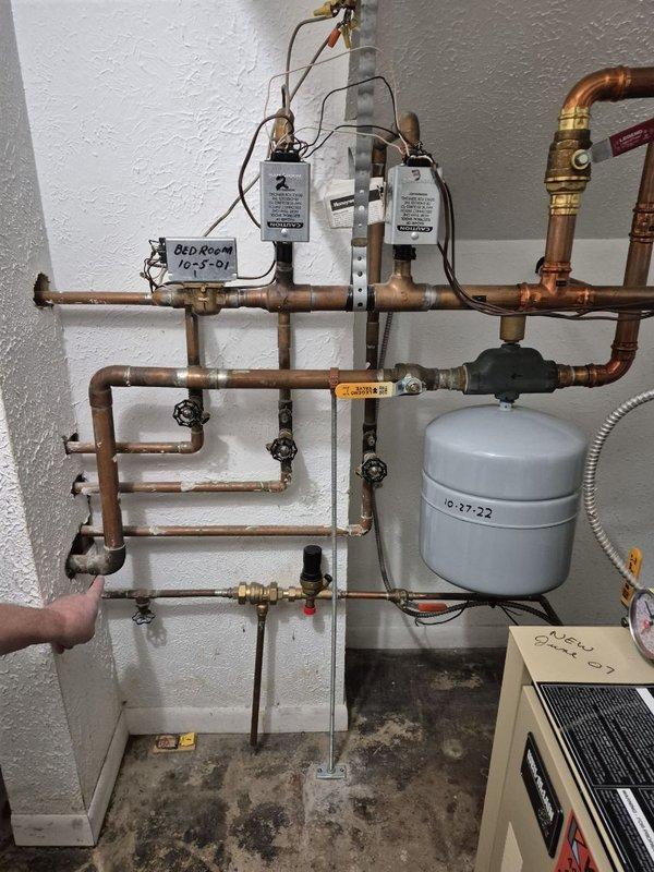 Repaired leaking copper pipe joint on hot water line connected to boiler system. Identified significant green-blue corrosion at connection point, indicating prolonged moisture exposure. Replaced damaged fitting and verified system integrity with pressure test.