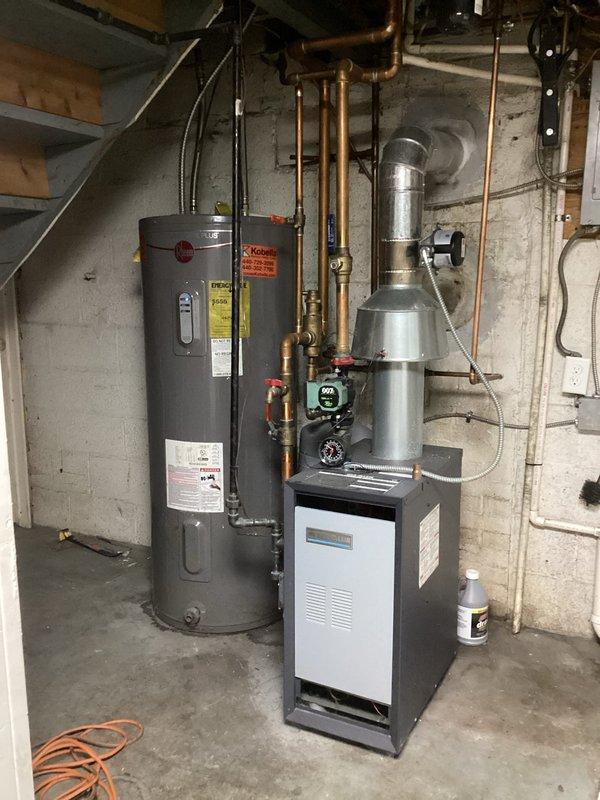 Conducted a consultation for multiple plumbing projects including conversion from a 50-gallon electric water heater to a tankless system, replacement of well pump pressure tank, and reconfiguration of laundry supply lines. Visual inspection revealed existing water heater installation with copper supply lines against concrete block wall in utility area, and separate plumbing installation with PVC pipes requiring modification for laundry appliance repositioning. Provided comprehensive quotes for all requested services.