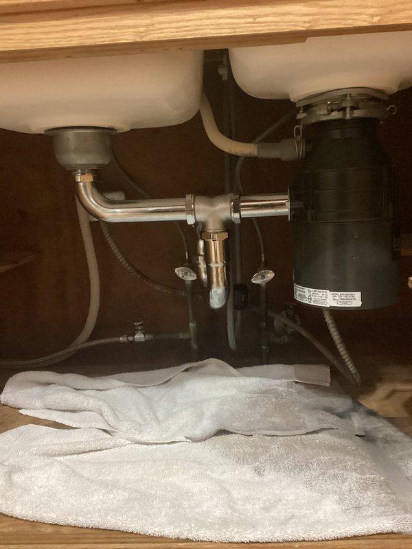 Responded to a water leak complaint where customer suspected the garbage disposal as the source. Upon inspection of the under-sink plumbing system, evaluated the black garbage disposal unit connected to chrome P-trap assembly and associated drain lines. Removed the garbage disposal as requested to eliminate the suspected leak source.
