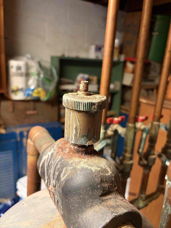 Responded to service call regarding buzzing sound from pump. Inspection revealed a heavily corroded air vent/bleeder valve with significant mineral buildup and oxidation on connecting pipes. Also identified green circulation pump within copper pipe system showing substantial discoloration and oxidation at joints and connections. Documented condition with photos for future reference.