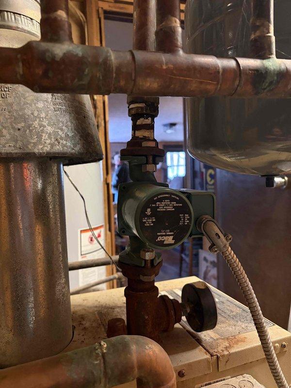 Responded to service call regarding buzzing sound from pump. Inspection revealed a heavily corroded air vent/bleeder valve with significant mineral buildup and oxidation on connecting pipes. Also identified green circulation pump within copper pipe system showing substantial discoloration and oxidation at joints and connections. Documented condition with photos for future reference.