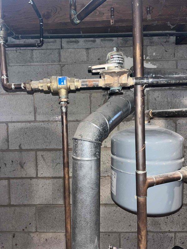 Responded to service call for non-functioning boiler system. Inspected aging copper piping installation which showed significant oxidation and corrosion. Identified and repaired a leak at the elbow joint where dampness and rust were present, and verified proper operation of the pilot light and pressure systems. System was restored to normal heating function.