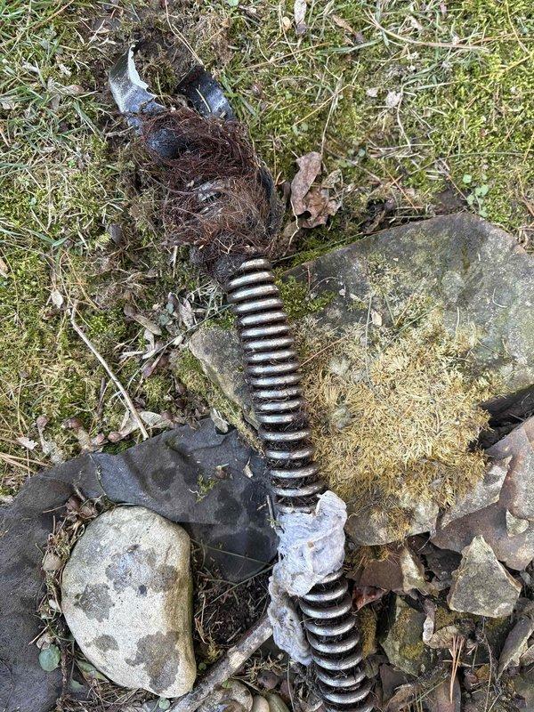 Cleared main drain backup in basement clean-out using electronic locator equipment to identify blockage location. Removed severely corroded metal spring coil that was causing the obstruction, which had accumulated organic debris and was preventing proper drainage.
