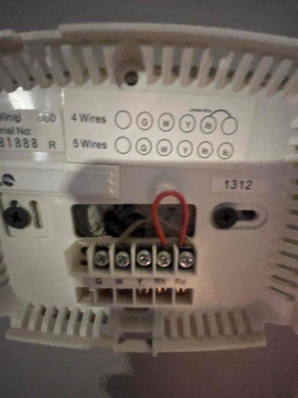 Inspected customer's existing HVAC system to evaluate feasibility of adding air conditioning. Examined 14-year-old furnace and thermostat wiring configuration (G,W,Y,Rh,Rc terminals with jumper). Documented basement mechanical area including existing ductwork and connections for potential AC integration.
