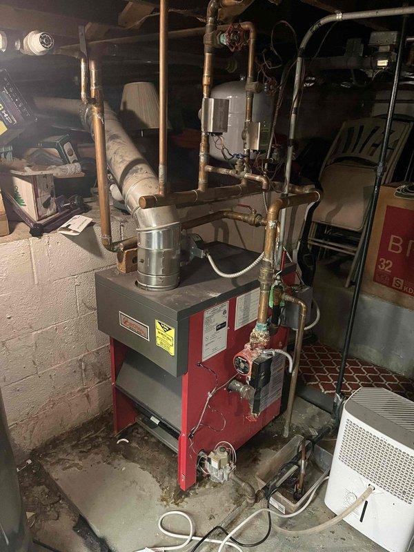 Responded to service call for boiler leaking from base. Upon inspection, discovered significant corrosion on heat exchanger coils with rust formation. Diagnosed failed gasket causing water leak. Documented extensive deterioration of internal components that will require replacement parts on follow-up visit.
