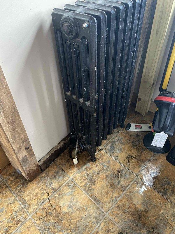 Returned to complete boiler installation. Observed vintage cast iron radiator with signs of moisture around base. Identified damaged fins with corrosion and debris accumulation requiring cleaning. Installation work remains in progress with additional components to be installed at next visit.