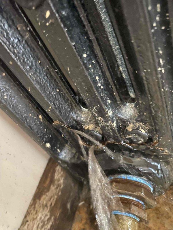 Returned to complete boiler installation. Observed vintage cast iron radiator with signs of moisture around base. Identified damaged fins with corrosion and debris accumulation requiring cleaning. Installation work remains in progress with additional components to be installed at next visit.
