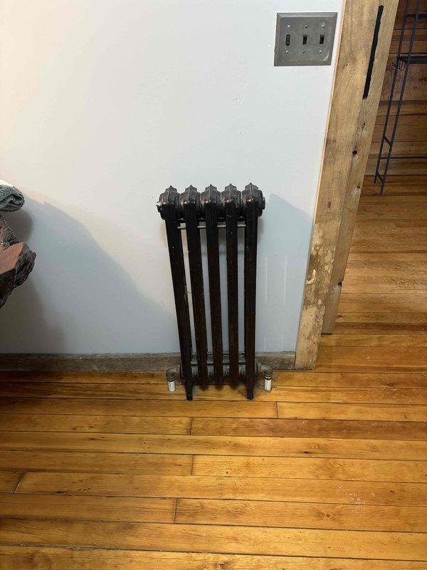 Conducted on-site assessment for installation of replacement boiler in laundry room to service existing cast iron radiator heating system. Documented current installation including vintage cast iron radiators, existing plumbing connections, and surrounding room configurations to determine appropriate specifications for new boiler unit.