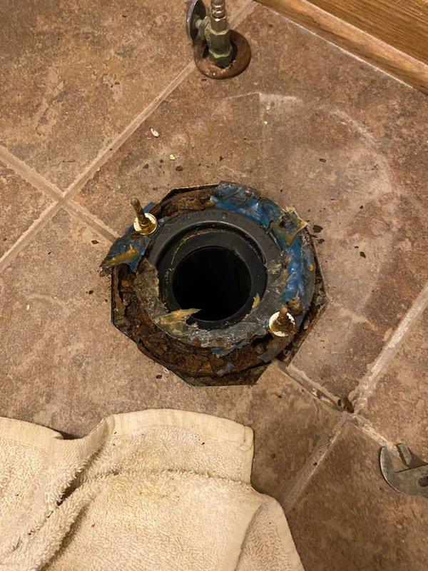 Diagnosed water leak in bathroom area with significant corrosion on toilet flange. Inspected PVC drainage pipe in subfloor structure, noting deterioration and potential water damage. Advised homeowner that floor joists and subflooring require repair before plumbing work can continue; homeowner will schedule return service after structural repairs are completed.