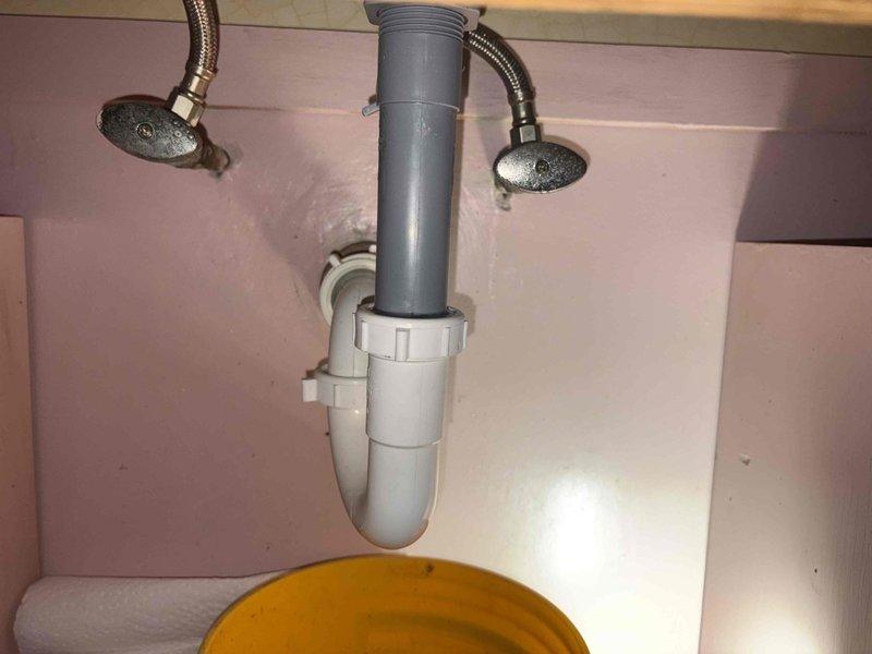 Cleared severe bathroom sink clog by removing P-trap and extracting significant buildup of dark sludge. Disassembled drain assembly, collected waste material in containment vessel, then reassembled plumbing components and verified proper drainage function.