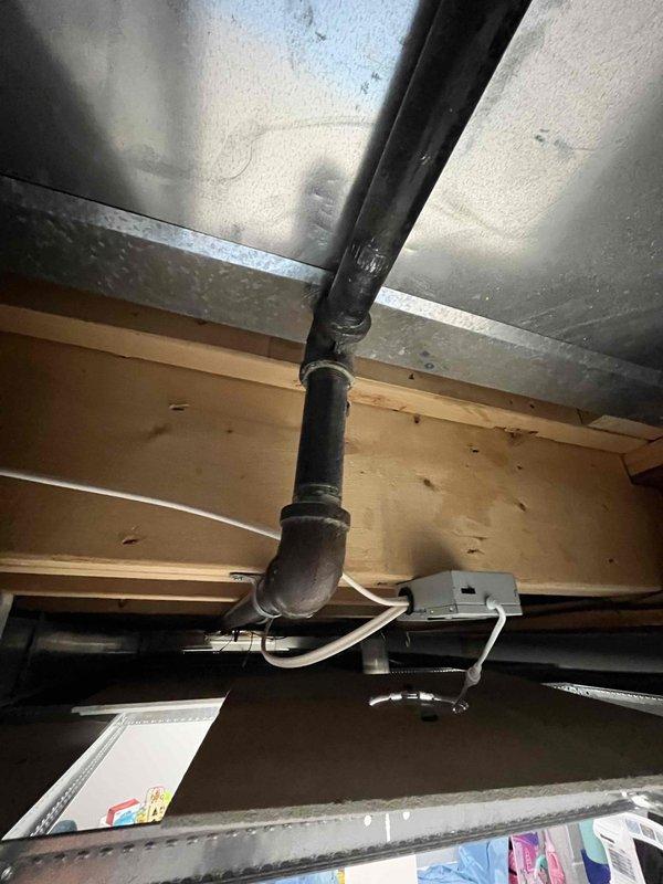 Responded to active gas leak notification (65w AH) previously identified by gas company. Inspected exterior gas valve connection showing signs of weathering and corrosion at foundation area. Examined interior gas line infrastructure including black PVC pipe installation with 90-degree bend running along wooden joists near electrical junction box. Performed pressure test to locate and repair leak, ensuring system integrity and safety compliance.