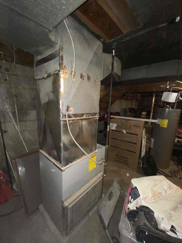 Performed inspection and measurement of existing HVAC system in utility room for potential replacement. Current setup includes an aging furnace with connected ductwork and insufficient insulation, positioned near water heater in basement area. Measurements were taken and documented to prepare comprehensive replacement estimate for customer who may have communication limitations due to spam filtering.