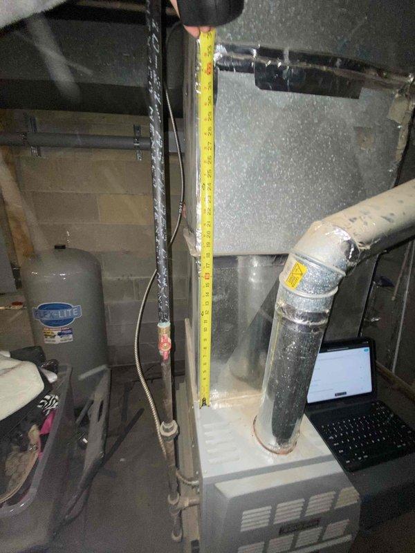 Performed inspection and measurement of existing HVAC system in utility room for potential replacement. Current setup includes an aging furnace with connected ductwork and insufficient insulation, positioned near water heater in basement area. Measurements were taken and documented to prepare comprehensive replacement estimate for customer who may have communication limitations due to spam filtering.