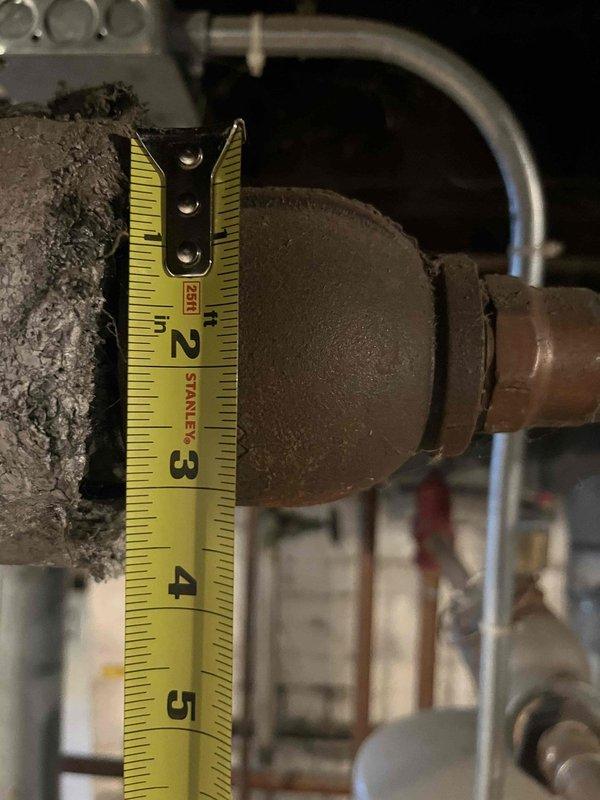 Conducted assessment of aging boiler system showing significant corrosion and deterioration. Measured pipe connections and examined junction points in utility area, noting multiple issues including rust damage and poor insulation. Customer is considering replacement with a combi system after property experienced freezing damage over winter; awaiting follow-up to discuss replacement options.