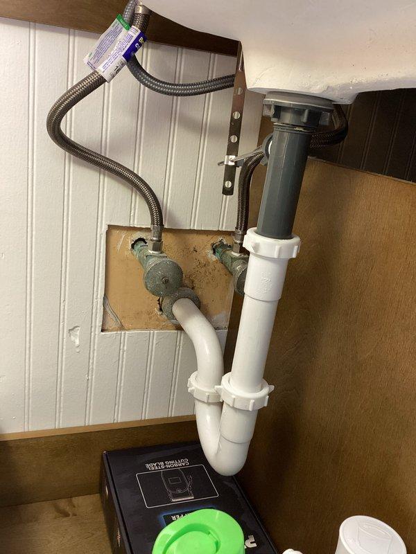 Responded to service call for drainage issues affecting washing machine discharge into utility tub and kitchen sink backup. Inspected plumbing system including P-trap configuration, drain assembly, and water supply lines. Successfully cleared blockage in main drain line that was causing multiple fixture backup, restoring proper drainage function to both the utility tub and kitchen sink.