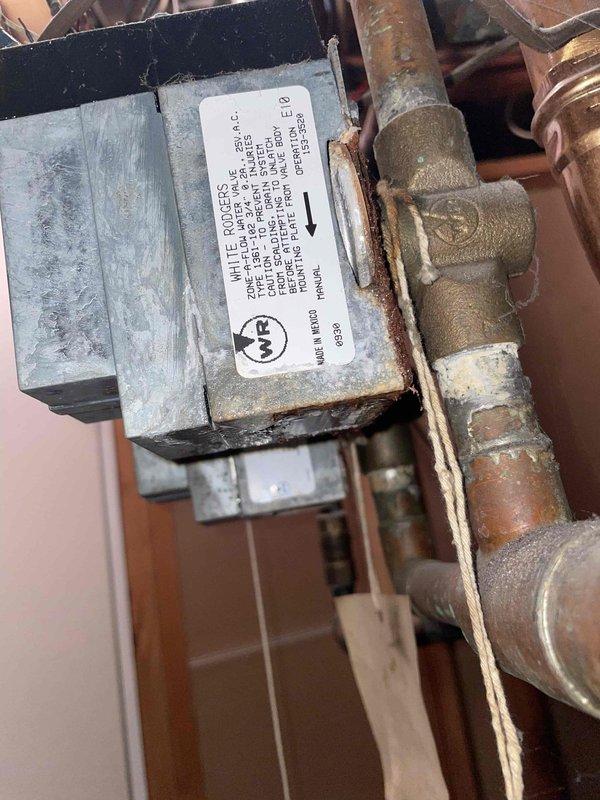 Inspected boiler with pilot light ignition failure occurring for over one year and identified White-Rodgers automatic valve leaking. Documented significant oxidation and corrosion on copper pipes connecting to control assembly, with incomplete ignition sequence preventing proper system operation.