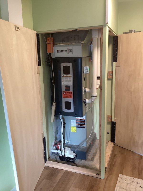 Conducted site evaluation of existing Kobella HVAC system for potential AC or mini-split replacement options. Unit is installed in wall enclosure with PVC drainage pipes and condensate pump. Previously replaced furnace remains in good working condition.