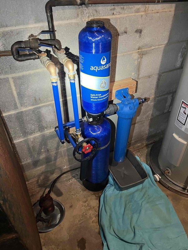 Responded to service call regarding backup in main laundry line where sewage was surfacing around basement drain despite previous jetting of main septic line by another contractor. Inspected well pressure system including WELL-TROL pressure tank, associated valves, and pressure gauges. Also examined whole-house water treatment system featuring Aquasalt water conditioner and filtration components. Diagnosed issues with both the sewage backup and pressure tank system.