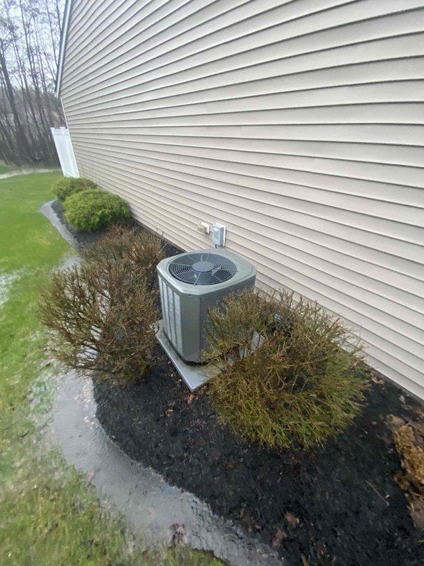 Conducted inspection of 19-20 year old gas furnace system and exterior condenser unit. Documented existing HVAC equipment condition including the outdoor AC unit positioned on concrete pad adjacent to home with beige vinyl siding, electrical disconnect box, and surrounding landscape features. Prepared replacement estimate for aging system based on comprehensive site evaluation.
